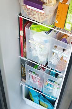 the refrigerator door is open and filled with plastic containers, food, and other items