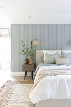 a bed sitting in a bedroom next to a wooden table and lamp on top of a rug