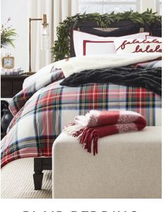 a bed with plaid sheets and blankets on top of it in front of a window