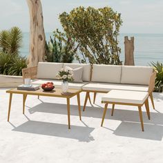 a couch and table on the beach with trees in the backgroung area