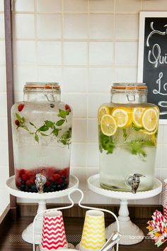 two mason jars filled with lemons, raspberries and limeade sitting on top of a counter