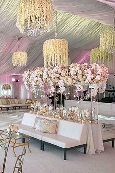 an elegant wedding reception setup with chandeliers and floral centerpieces on the ceiling