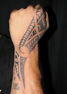 a man's arm with tattoos on it and his hand holding the wrist tattoo