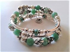 KY-13 - Silver plated metal tube beads surround faceted, mint green jade gemstones and white Czech glass pearls.  Daisy spacers and double flower bead caps (lead and nickel free) and small,  bi-cones accent these gemstones.  A double-sided open heart charm falls from one end of this bracelet. Silver Beaded Jade Bracelets, Silver Jade Beaded Bracelets, Elegant Green Wire Wrapped Beaded Bracelets, Bracelet Ends, Memory Wire Jewelry, Beaded Memory Wire Bracelets, Memorial Bracelet, Memory Wire Bracelet, Beads Bracelet Design