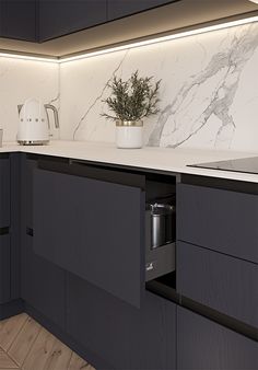 a kitchen with black cabinets and white marble backsplash, lights above the sink