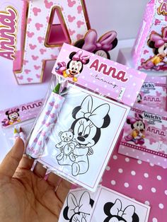 a hand holding up a minnie mouse coloring book with other disney characters in the background