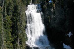 a large waterfall surrounded by trees and snow