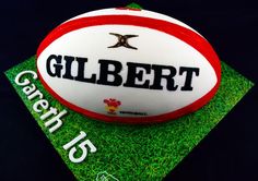 a cake made to look like a football on top of green grass with the name gilbert written on it