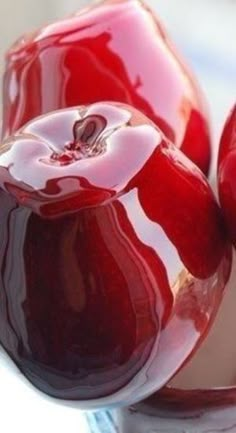 two red apples sitting in a glass bowl