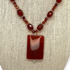 This is a beautiful, red carnelian beaded pendant choker. Oval and round carnelian beads are separated by sterling caviar-style beads on the estate necklace. The pendant is a rectangular red carnelian. This semi-precious gemstone symbolizes health, luck, and royalty. It is a variety of the silica mineral chalcedony colored by impurities of iron oxide. The necklace fastens with a silver toggle clasp. Brand: Unknown Markings: Unmarked metal; this item has been tested to confirm metal content. Mate Red Beaded Necklaces, Multi Gemstone Ring, Red Carnelian, Pendant Choker, Carnelian Beads, Beaded Pendant Necklace, Beaded Hoop Earrings, Beaded Hoops, Hand Jewelry