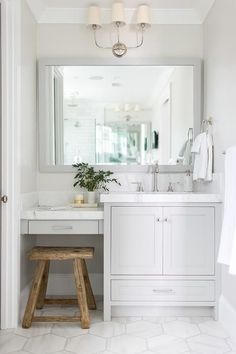 a white bathroom with a stool and mirror