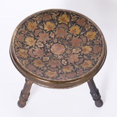 a small wooden stool with flowers painted on the top and legs, against a white background