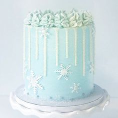 a blue frosted cake with white icing and snowflakes on the top