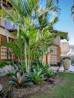 a house with lots of plants in front of it and trees around the outside area