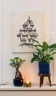 two potted plants sit on a mantle in front of a painting and candle holder