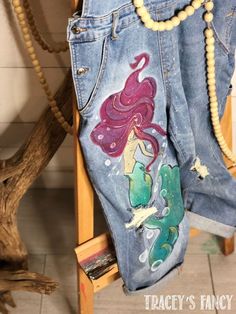 an old pair of jeans with mermaids painted on them and beads hanging from the back