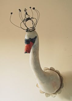 a white bird with a crown on it's head hanging from a wall in a room