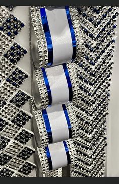 two rolls of blue and white ribbon hanging from the side of a dress with beading on it