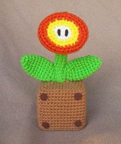 a crocheted flower on top of a brown object with green leaves and dots