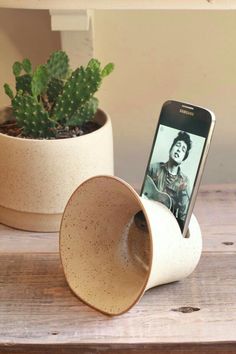 a cell phone sitting in a cup on top of a table next to a plant