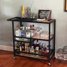 a bar cart filled with liquor bottles and glasses on top of a hard wood floor