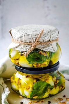 three jars filled with food sitting on top of each other next to a book page