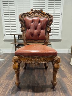 an ornate wooden chair with red leather upholstered seat and foot rests on a hard wood floor