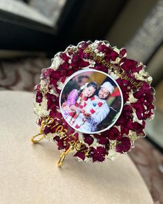 an image of two children in a frame surrounded by red and white flowers on a table