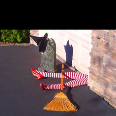 a broom is laying on the ground next to a mailbox and a black cat