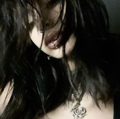 a woman with long black hair and tattoos on her chest is staring at the camera