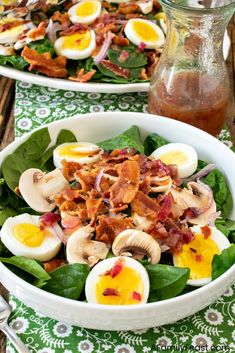 two white bowls filled with salad and hard boiled eggs on top of spinach leaves