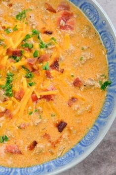 a blue and white bowl filled with soup topped with meat, cheese and veggies