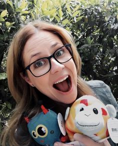 a woman holding two stuffed animals in front of her face and making a funny face