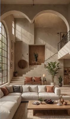 a living room filled with lots of furniture next to a stair case in front of a window