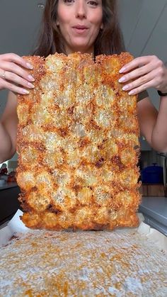 a woman holding up a large pizza in front of her face