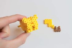 a hand holding a yellow lego object next to another toy