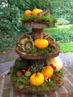 a three tiered planter with pumpkins and gourds on the top