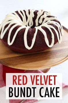 a red velvet bundt cake with white icing on a wooden platter next to a fork