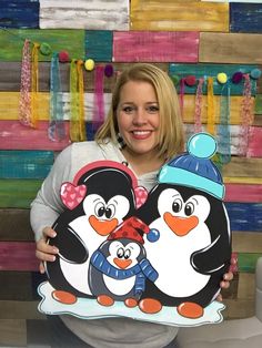 a woman holding two penguins in front of a colorful wall