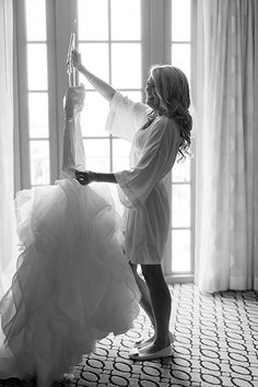 a woman in a wedding dress is holding up her dress