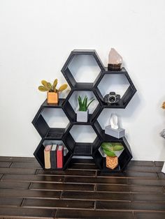 a shelf with books, plants and other items on it in front of a white wall