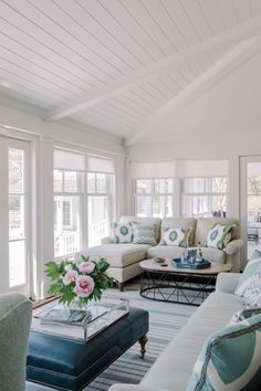 a living room filled with lots of furniture next to large window covered in white walls