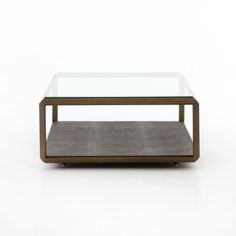 a coffee table with a glass top and metal frame, on a white surface in front of a plain background