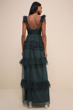 the back of a woman wearing a dark green dress with tiered layers and ruffles