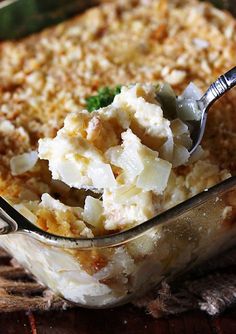 a casserole dish filled with potatoes and cream cheese on a wooden table top