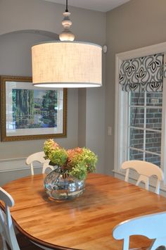 a wooden table with white chairs around it and a vase filled with flowers on top