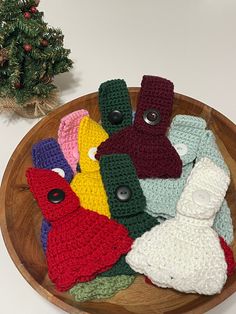 there are many crocheted items in the bowl on the table next to a small christmas tree