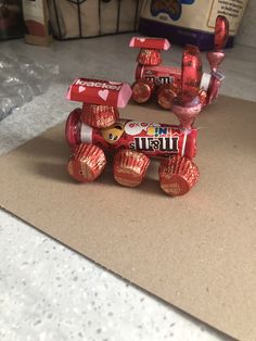 a small toy car made out of candy bar wrappers on a counter next to other items