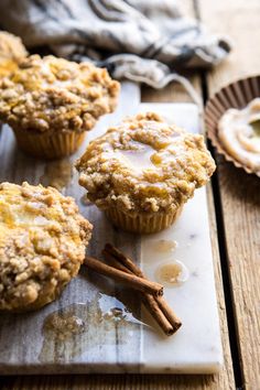 three muffins on a plate with cinnamon sticks