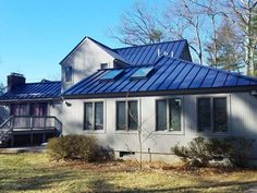 a house with a blue metal roof in the woods